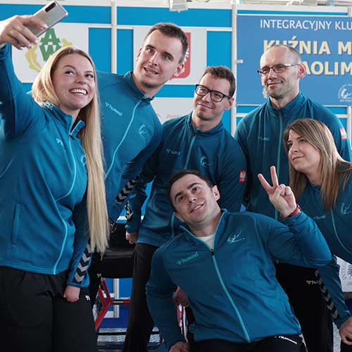 Obraz przedstawiający uśmiechniętych zawodników IKS-AWF w klubowych niebieskich dresach pozujących do wspólnego zdjęcia typu selfie